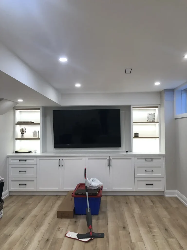 Finished basement media wall with recessed pot lights and LED-lit built-in shelving