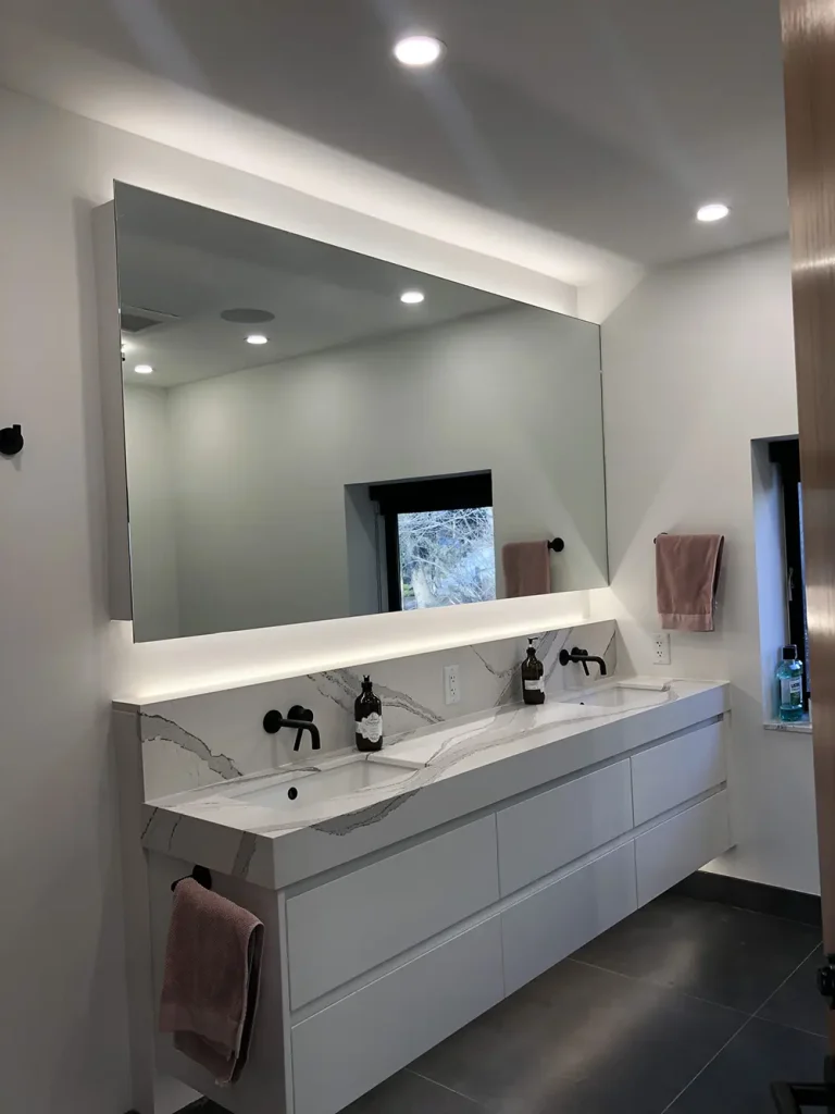 Bathroom vanity with a backlit LED mirror and recessed lighting