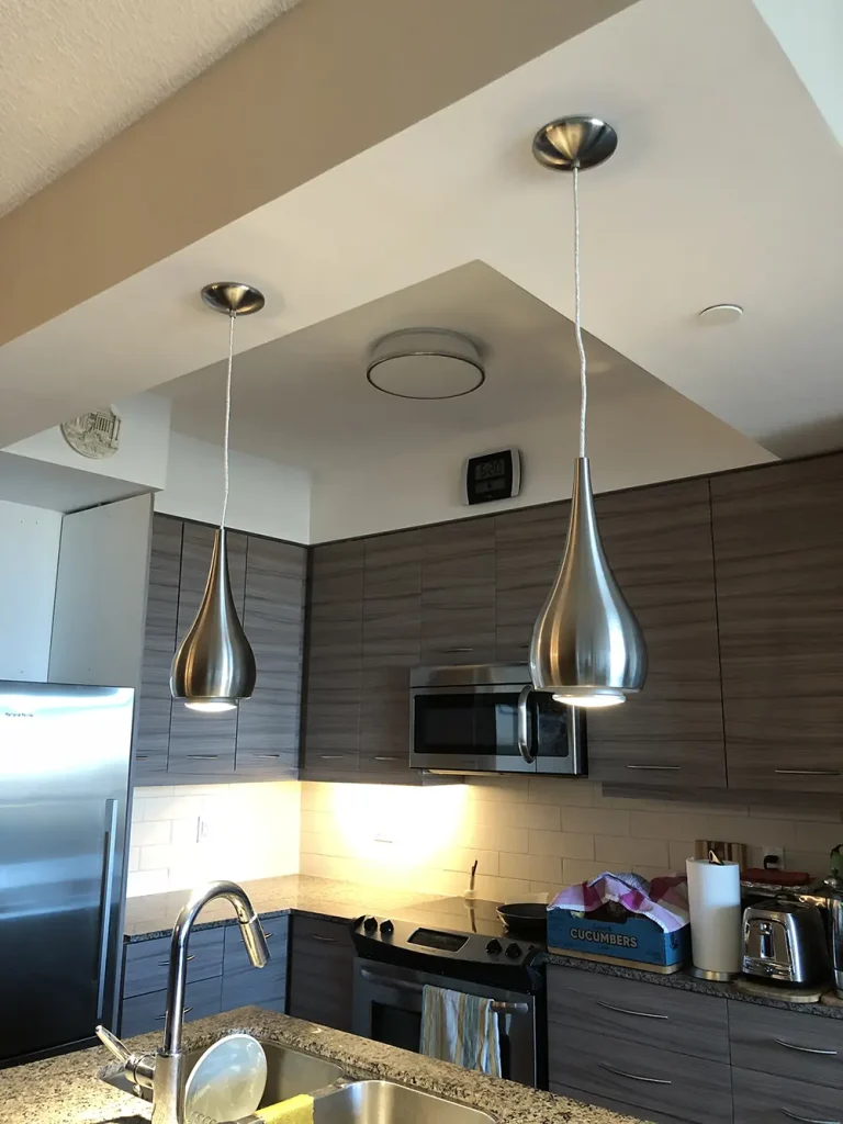 Condo kitchen with stainless teardrop pendants and under-cabinet task lighting