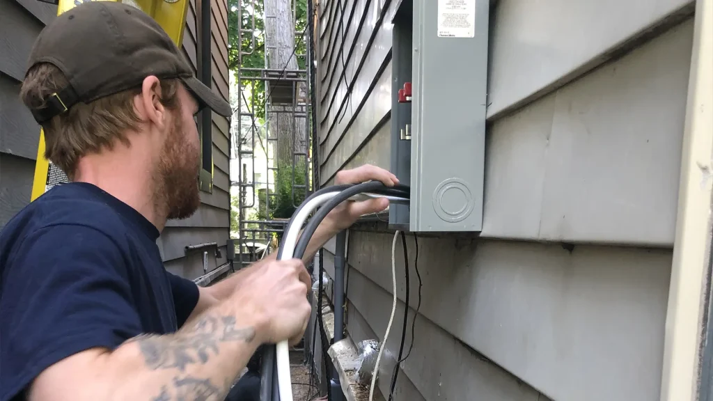 Electrician feeding service conductors into an exterior meter base