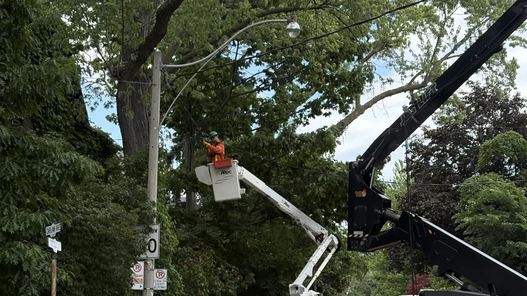 Utility crew working from a bucket truck on overhead lines above a residential street