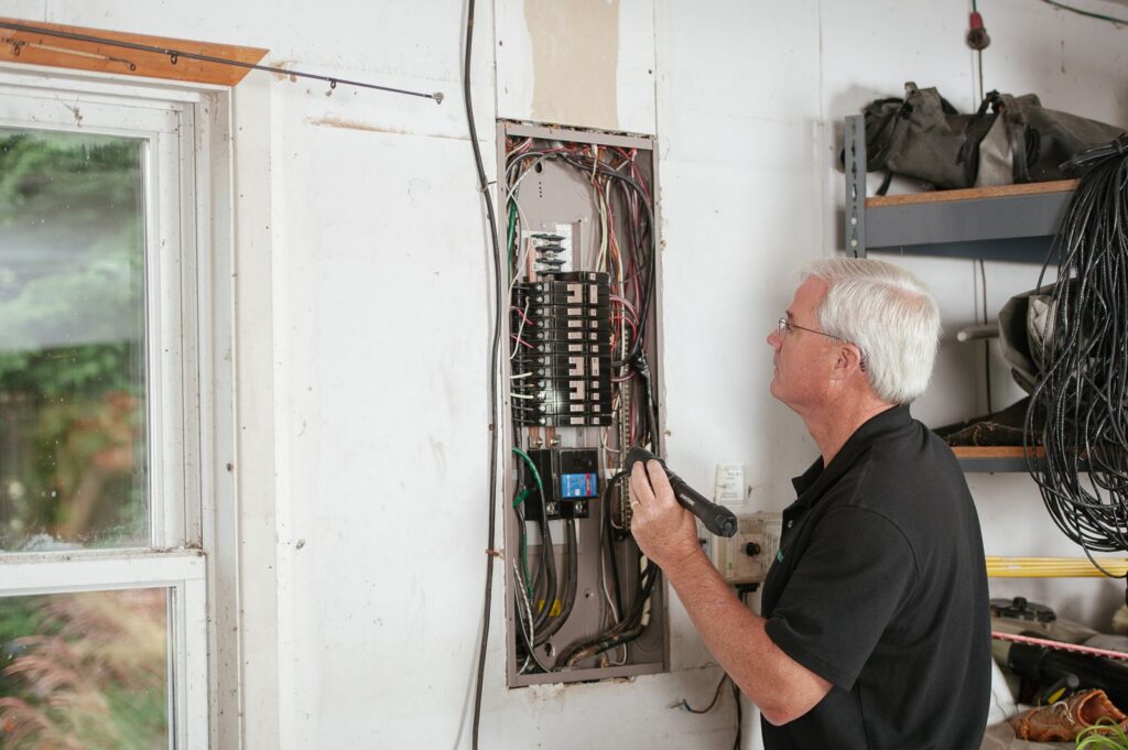 Electrician examining a residential breaker panel during an assessment